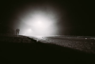 Silhouette people walking on shore of beach at night