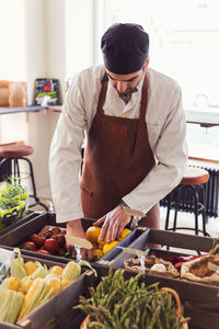 Male owner arranging vegetables at grocery store