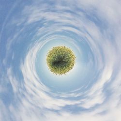 Little planet effect of grassy field against sky