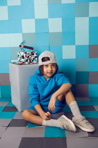 Fashion boy in blue clothes bites at a cake pixels with a pickaxe in the studio. birthday five years