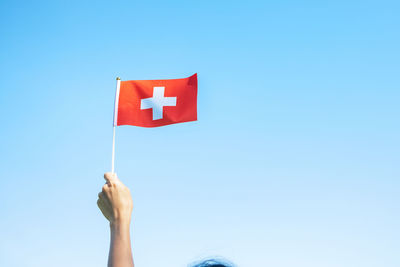 Low angle view of red flag against blue sky