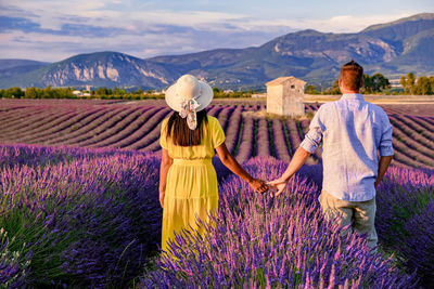 Rear view of couple walking on field against sky