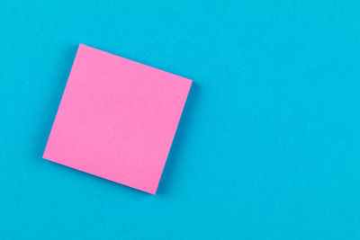 Directly above view of blank adhesive note on blue background