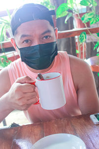 Portrait of young man drinking glasses on table