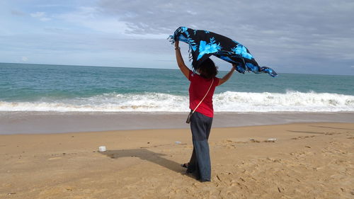 Full length of woman standing on beach against sky