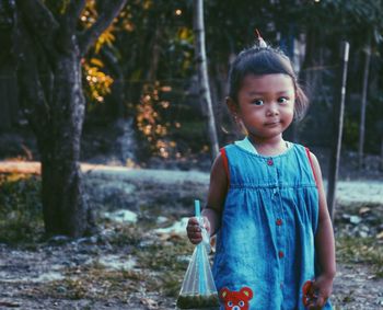 Portrait of cute girl standing against trees