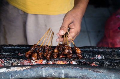 Midsection of man preparing meat on barbecue grill