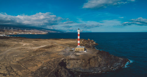 Lighthouse by sea against sky