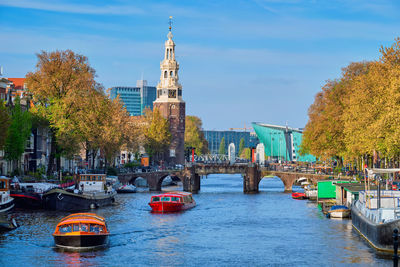 Amsterdam cityscape with canal boats and nemo science museum and montelbaanstoren tower. netherlands
