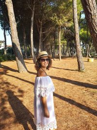 Portrait of woman standing by tree trunk