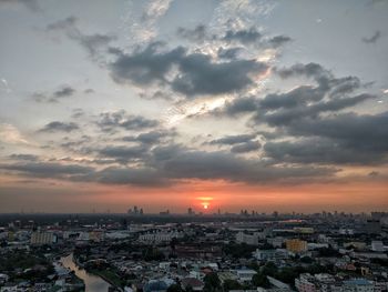 Aerial view of cityscape against cloudy sky during sunset