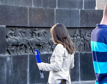 Rear view of women standing against wall