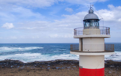 Lighthouse by sea against sky