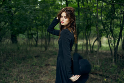 Young woman standing against trees