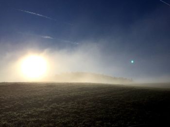 Sun shining through clouds over landscape