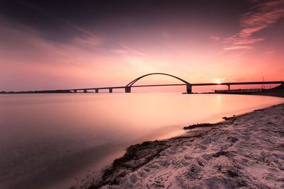Bridge over sea against romantic sky at sunset