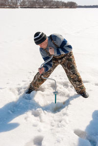 Mid adult man subglacial fishing in frozen lake