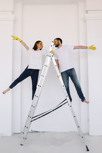 A young couple in love have moved into a new house and are making repairs painting white walls