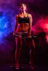 Full length portrait of young woman lifting dumbbell