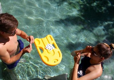 High angle view of friends playing cards in swimming pool