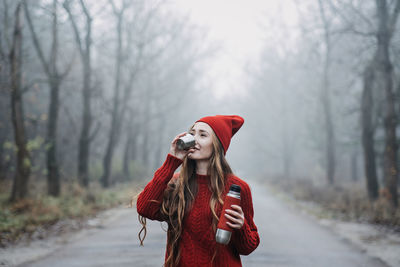 Alone young woman in red hat with thermos on nature background