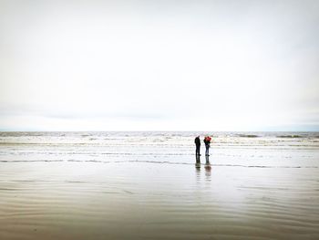 Family on shore at beach against sky