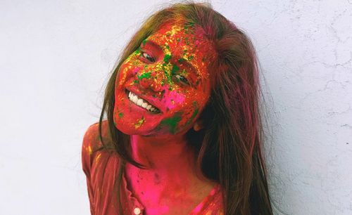 Portrait of woman with multi colored powder paint against wall