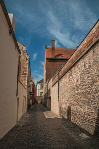 Footpath amidst buildings in town against sky