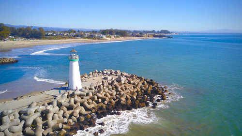 Scenic view of sea and light house against clear sky