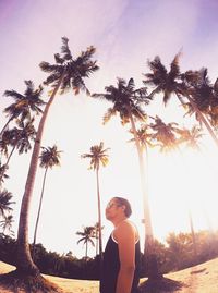 Low angle view of man standing on palm tree