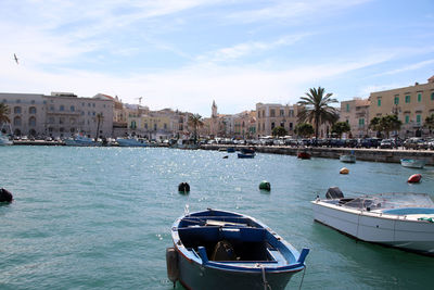 Boats in sea by city against sky