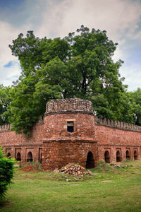 Old building by trees against sky