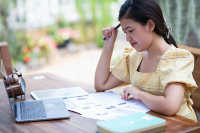 Young woman using mobile phone while sitting on table