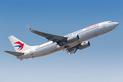 Low angle view of airplane flying against clear blue sky