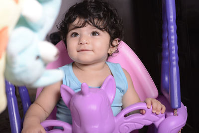 Baby girl sitting on unicorn swing at home