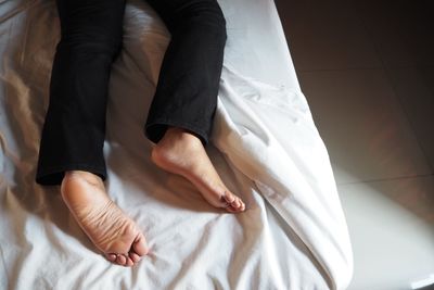 Low section of woman relaxing on bed