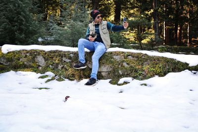 Full length of man sitting on snow covered land