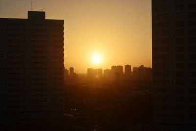 Modern cityscape against sky during sunset