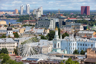 Ferris wheel and old bell tower on the cityscape of old podil in the city. 07.24.22 kyiv. ukraine.