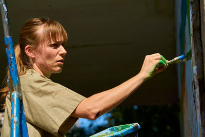 Portrait of young woman painting on wood