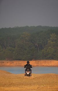 Rear view of man riding motorcycle against sky