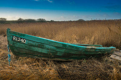 Abandoned boat on field against sky