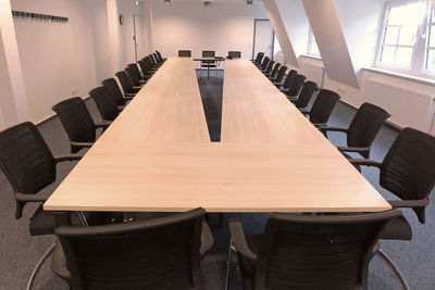 Empty chairs and table arranged in conference room