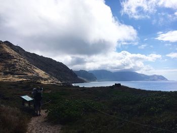 Scenic view of mountains by sea against cloudy sky