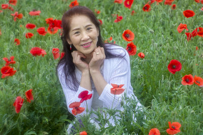 Portrait of smiling woman with red poppies in field