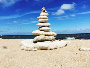 Stack of pebbles on beach against sky