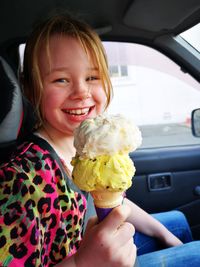 Portrait of smiling girl holding ice cream in car