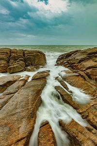 Scenic view of rocks in sea against sky