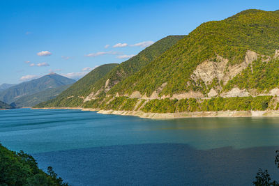 Scenic view of lake by mountains against blue sky