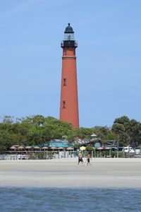 Lighthouse by sea against clear sky